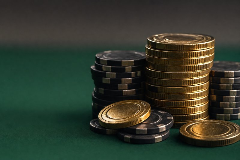 Gestapelte goldene Casino-Jetons auf grünem Filz im Streiflicht