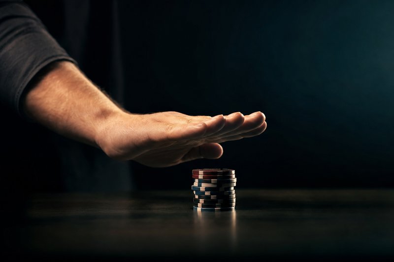 Eine Hand in Stopp-Geste über einem Stapel Casino-Jetons – Symbol für die Selbstsperre